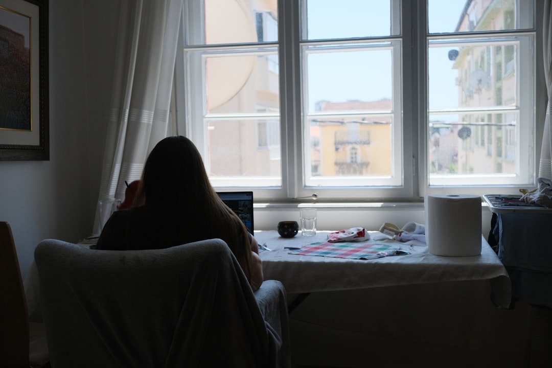 Home buyer working at a laptop near a bright window while preparing mortgage preapproval information