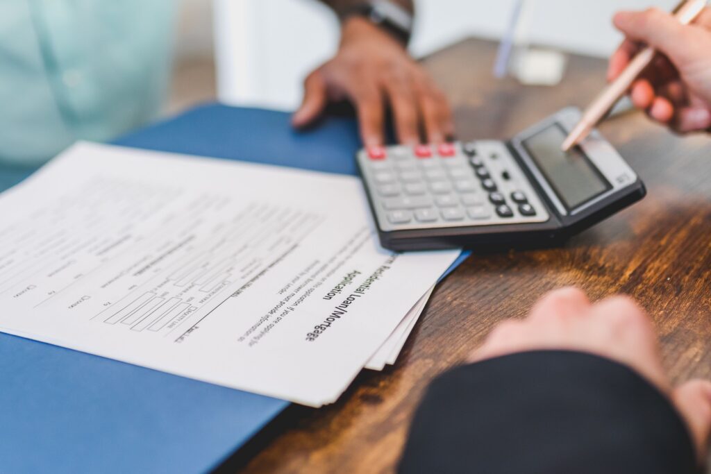 Calculator and real estate paperwork representing evidence review for a property valuation protest