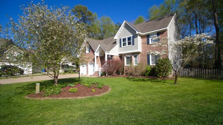 Residential home exterior with mature trees and lawn illustrating home-selling timing